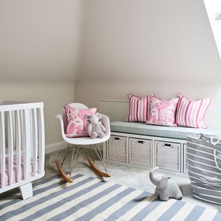 Warm grey nursery with pink accessories, rocker and striped rug