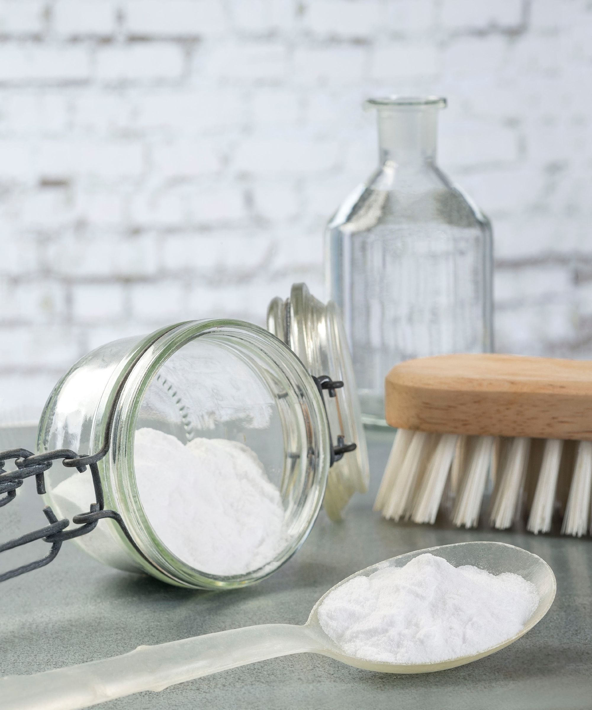 A container of baking soda beside a scrubbing brush