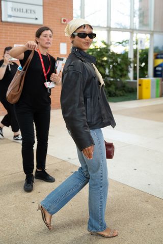 Taylor Russell wearing jeans, a leather and mules