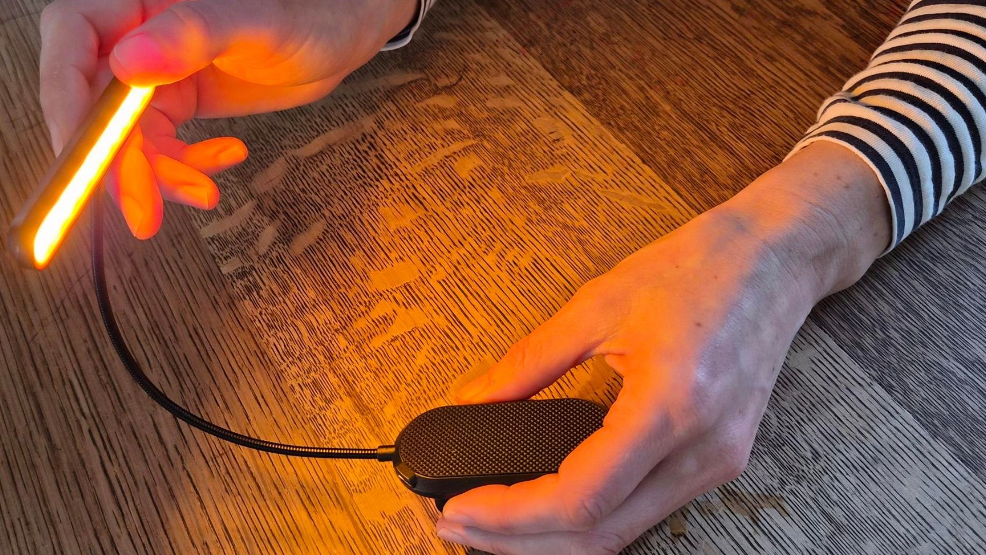 The image shows a woman wearing a long sleeved black and white stripey t-shirt holding a book light