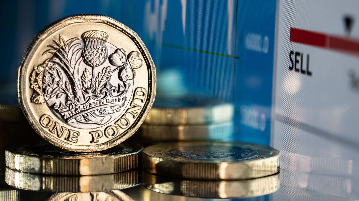 Close up of a stack of British pound coins against a financial currency chart and graph