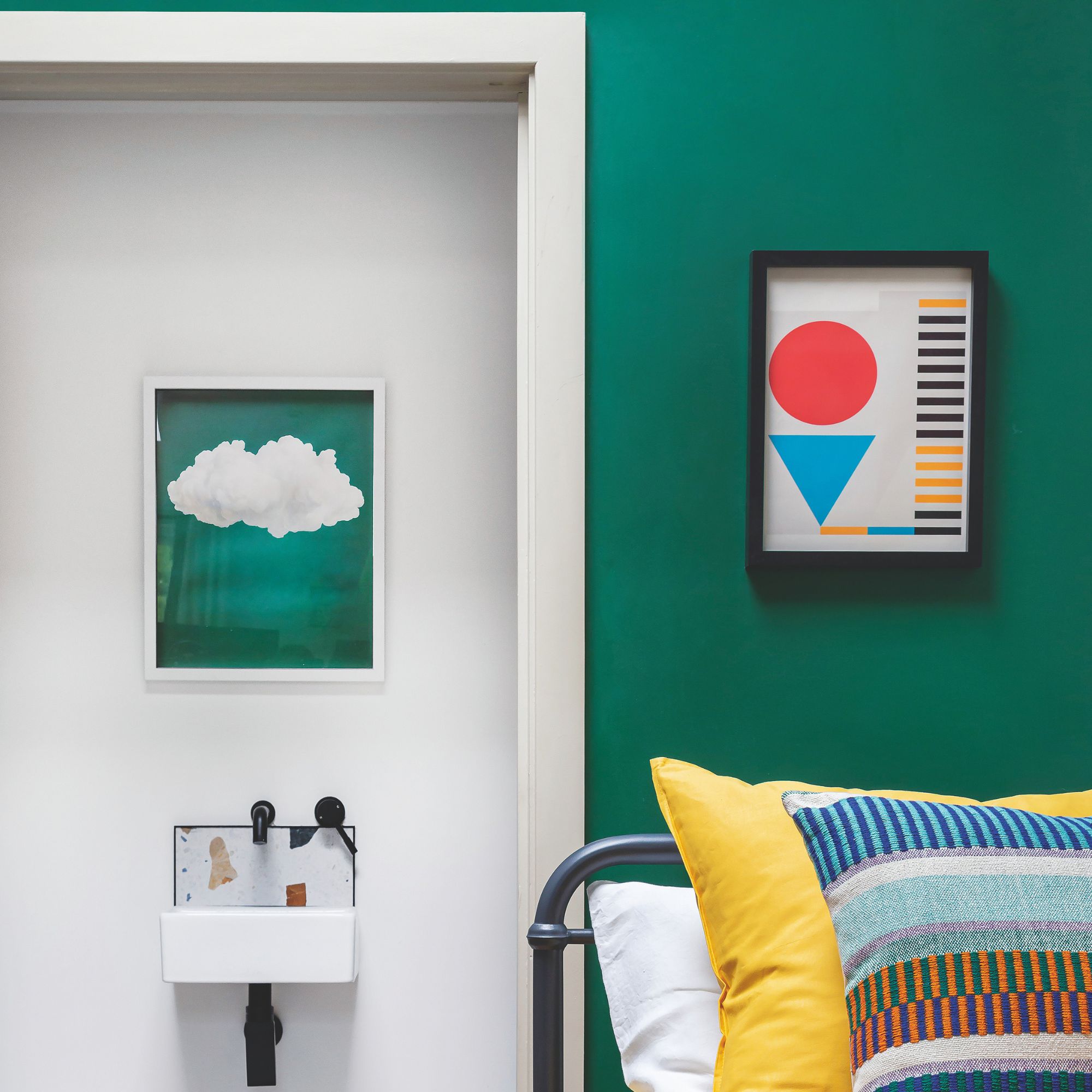A green teenage room with a black metal bed and colorful cushions, leading to a white suite
