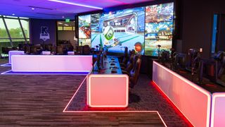 An esports venue a lit in neon lights with gamers POV displayed on an LED screen thanks to Marshall cameras. 