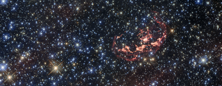 A new image taken with the Hubble Space Telescope shows the supernova remnant SNR 0509-68.7, also known as N103B. It's the wispy, elongated shell of red gas and dust near the top of the image.