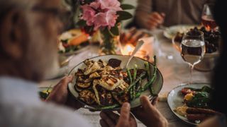 friends passing dinner plates around a table