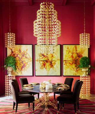grand dining room with red walls, gold artwork and gold chandelier