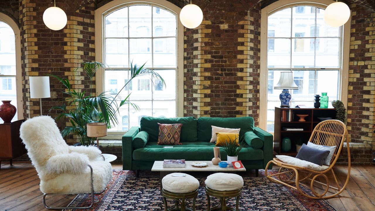 A living room setting with a green velvet sofa and exposed brick walls