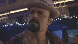 James Martinez as Angel Batista wearing his fedora in a bar looking concerned in Dexter: Original Sin