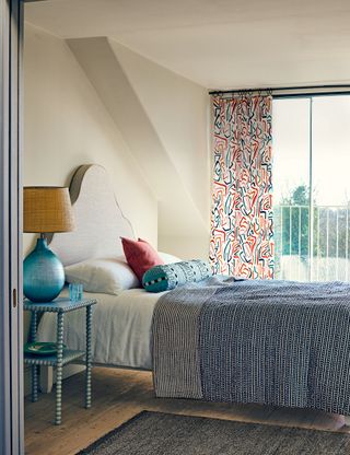 Small bedroom with curtains and patterned bedlinen
