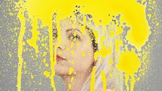 An illustration of a young woman's face has been painted over with bright splodges of yellow paint covering her face to depict brain fog