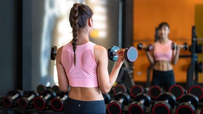 What dumbbell weights should I use? Woman standing in front of mirror at the gym