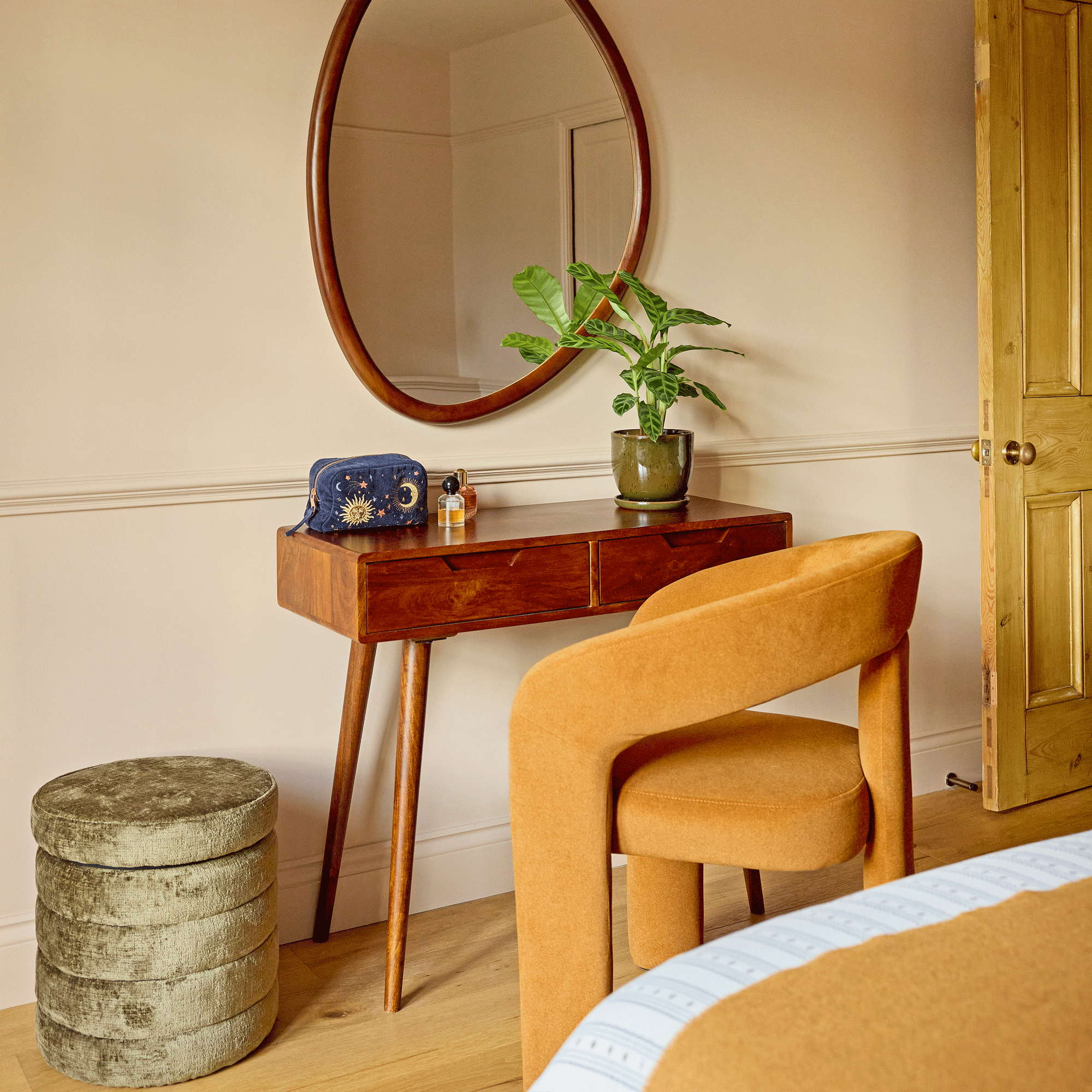 a bedroom with a dressing table area with a yellow upholstered chair