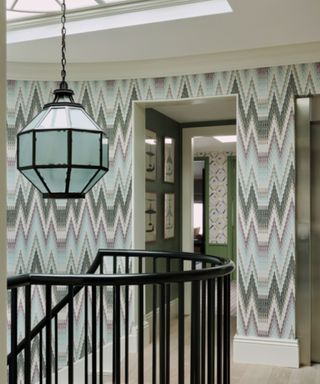 stairwell with patterned wallpaper and pendant light