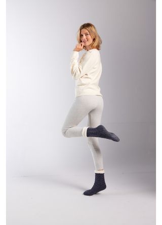 Model wears cream jumper with grey leggings and socks