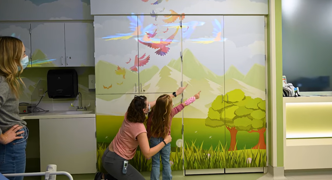 A child points at digital birds flying around a doctor&#039;s office.