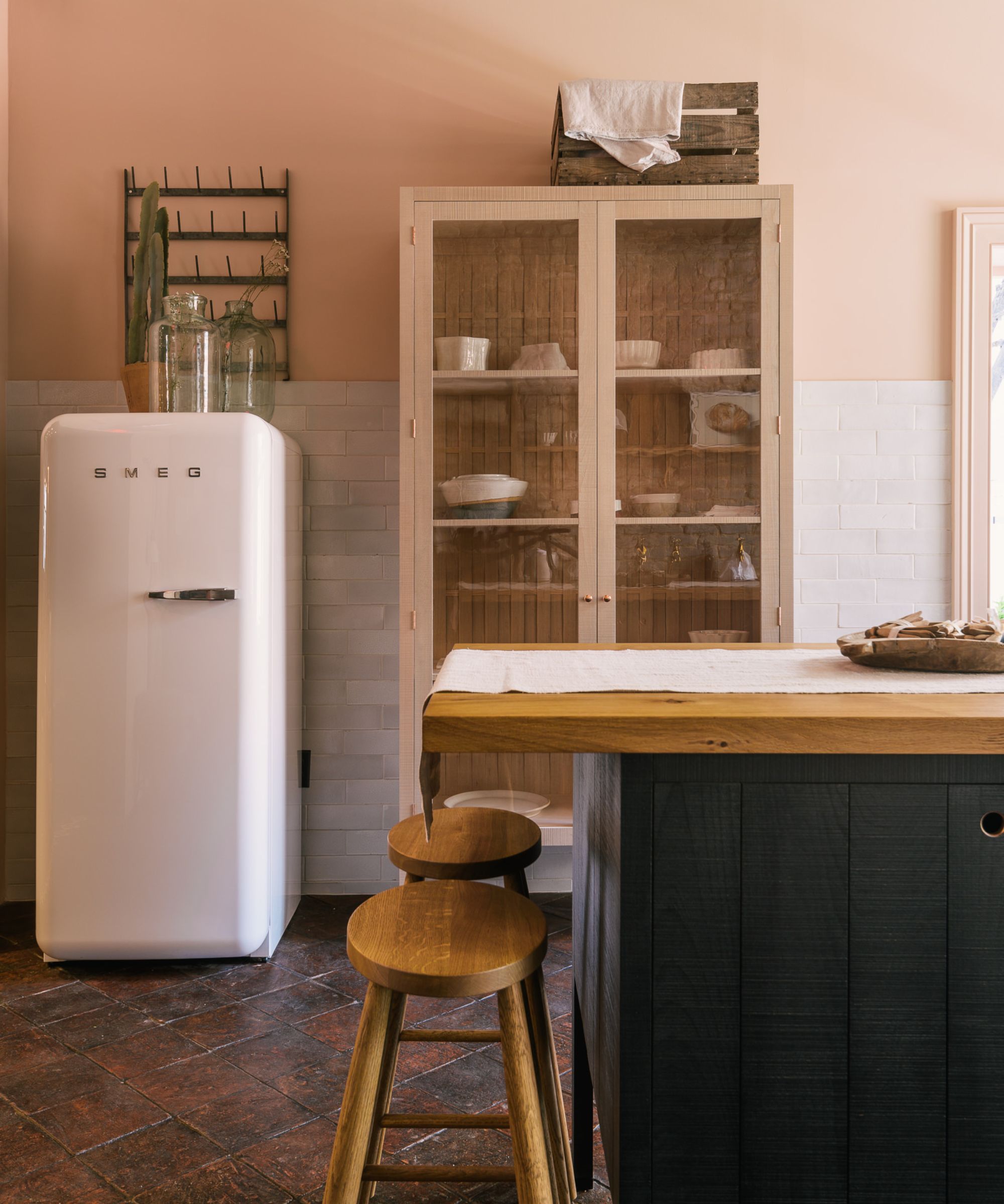 A pink and blue kitchen with wall tiles to the floor