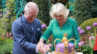 King Charles and Queen Camilla cutting a cake shaped like a crown