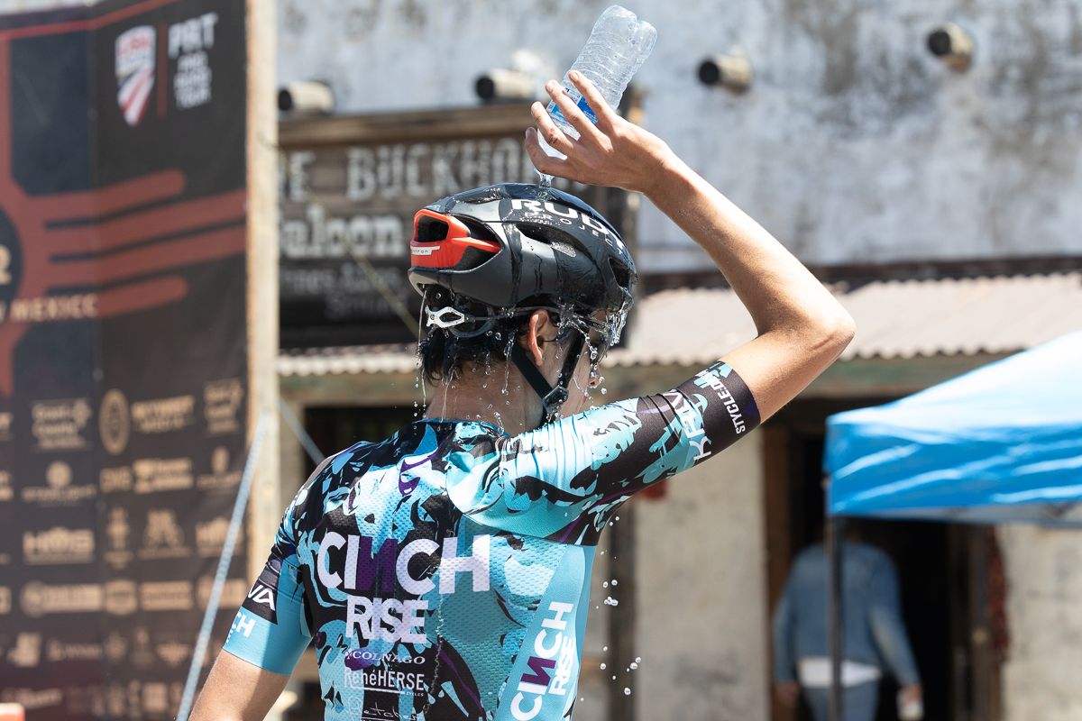 A team Cinch Rise rider dumps refershing cool water over his head on a stage that saw temperature and windspeed rising throughout the afternoon.