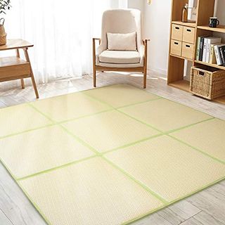 Large padded floor mat in yellow in a bright living room with mid century chair and table to the back left, and cubed book case to the right.