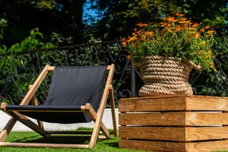 A deckchair in a backyard next to a wooden plant stand