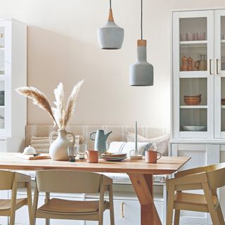 A dining room painted in an off-white shade with a seating bench and display cabinets painted in brilliant white