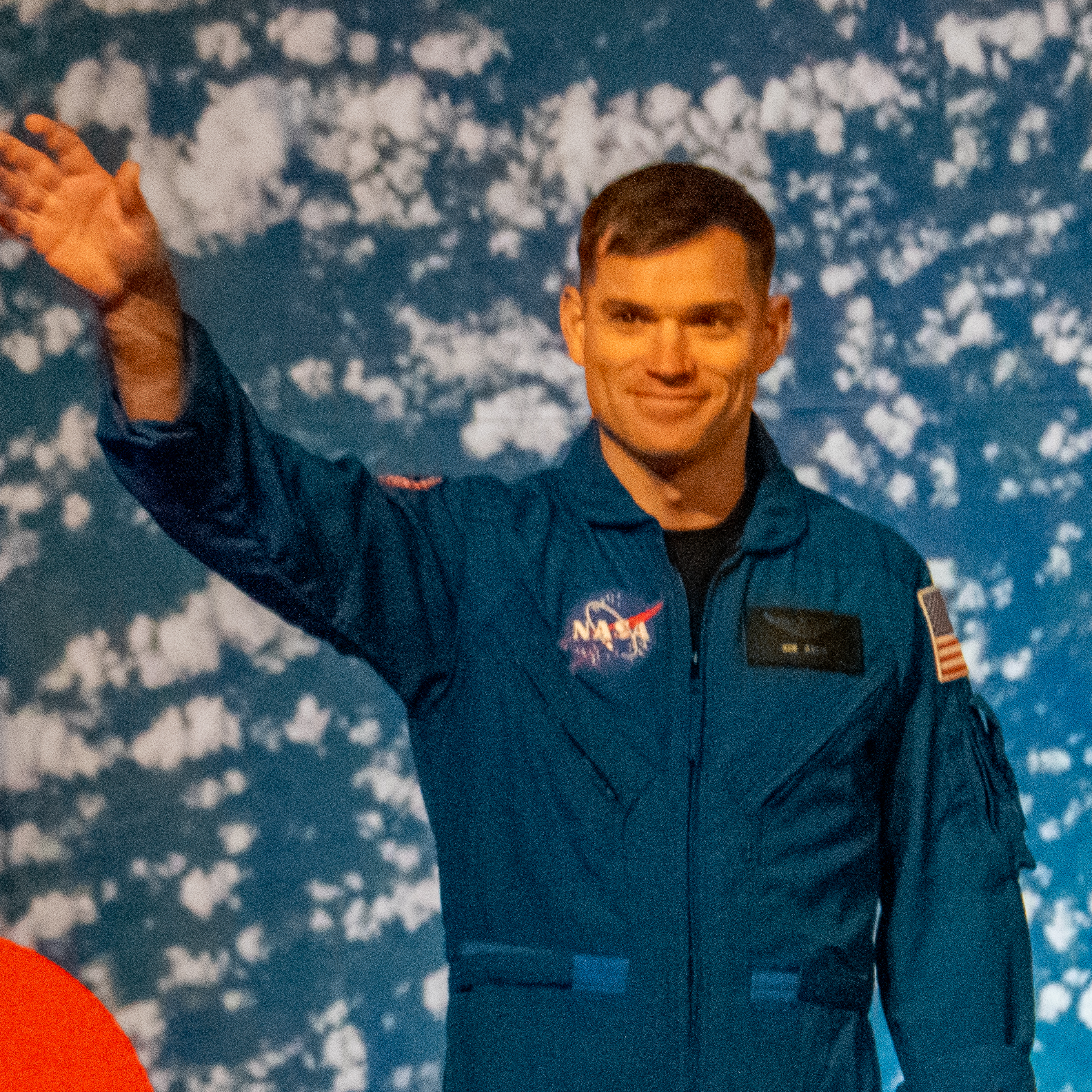 people in blue jumpsuits smile and wave.