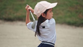 Young girl hitting a golf ball