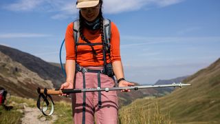 A woman holds a pair of Black Diamond Pursuit Trekking Poles in front of her.
