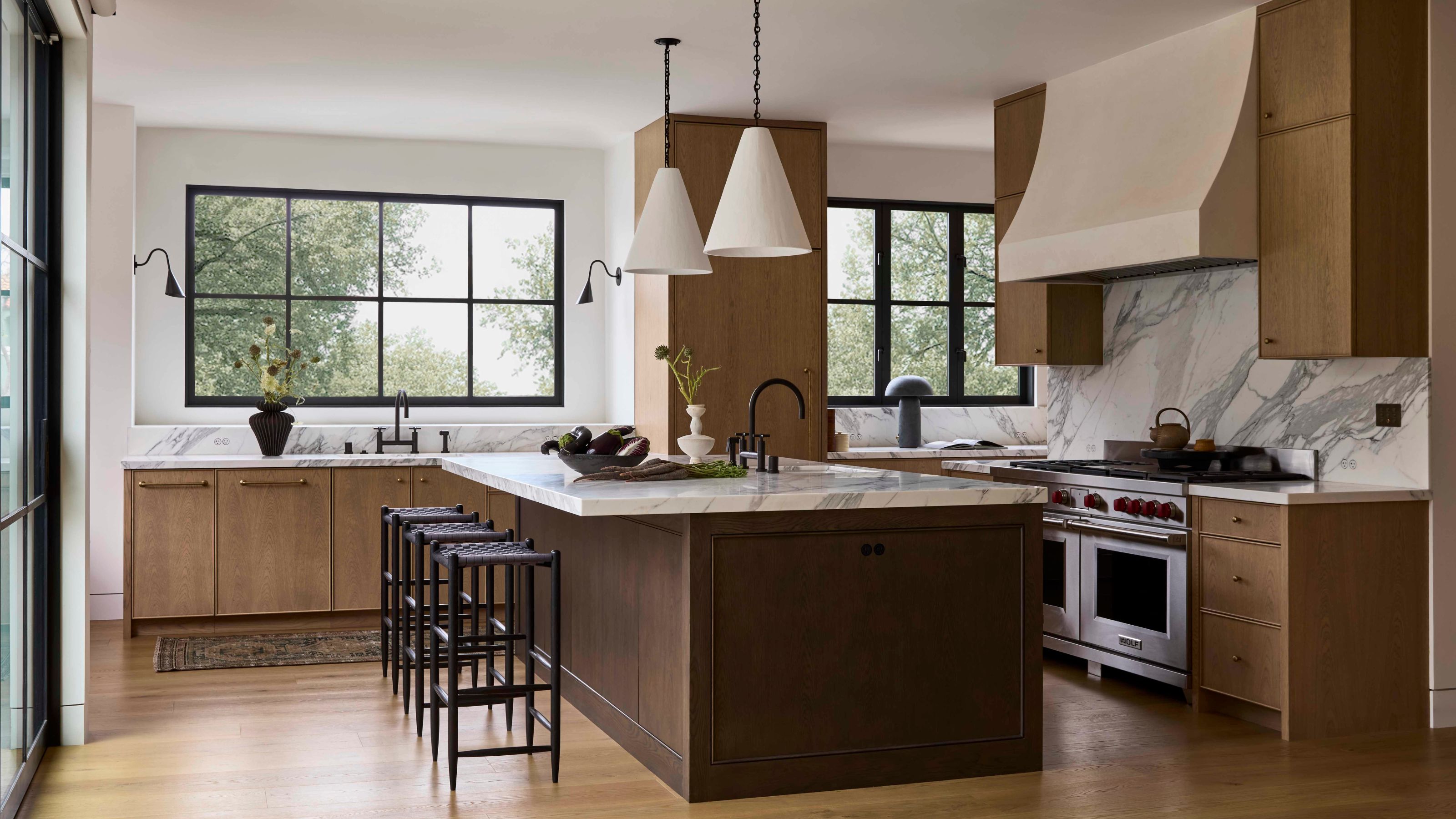 a large wabi sabi wooden kitchen with plaster pendants above a darker wooden island