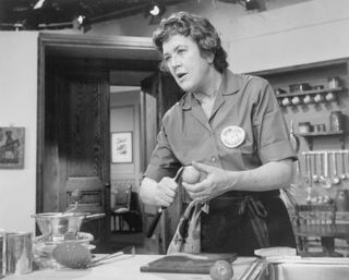 Julia Child, ebullient French chef, as she prepares a dish for a TV audience.