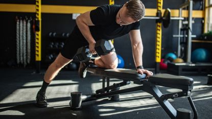 a man dumbbell rowing on a weight bench