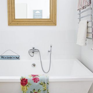 bathroom with white wall white bathtub and wooden frame mirror