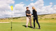 Male and female golfer shake hands on the green