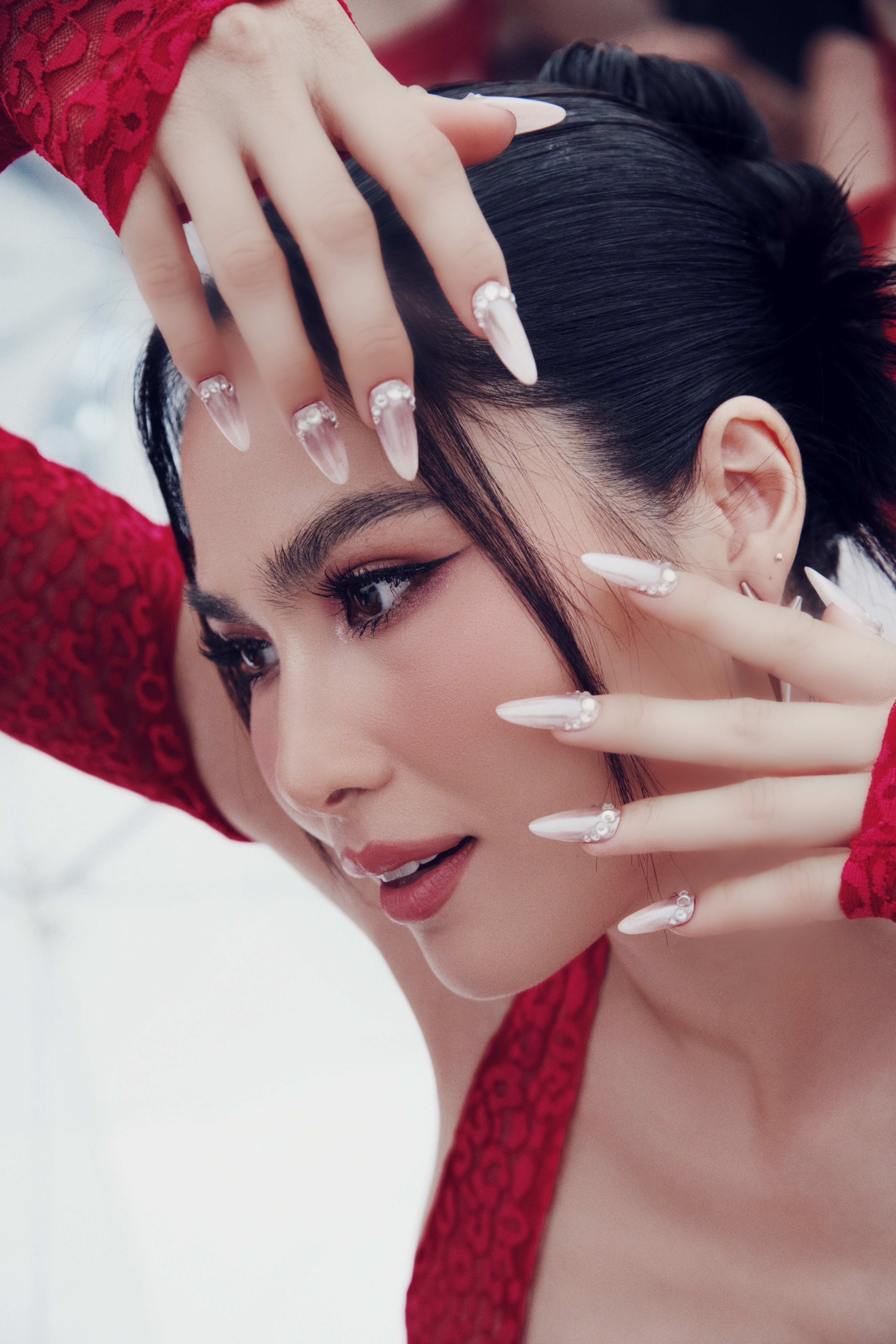A woman, Kim Truong, shows off her long manicure while posing for a photo.