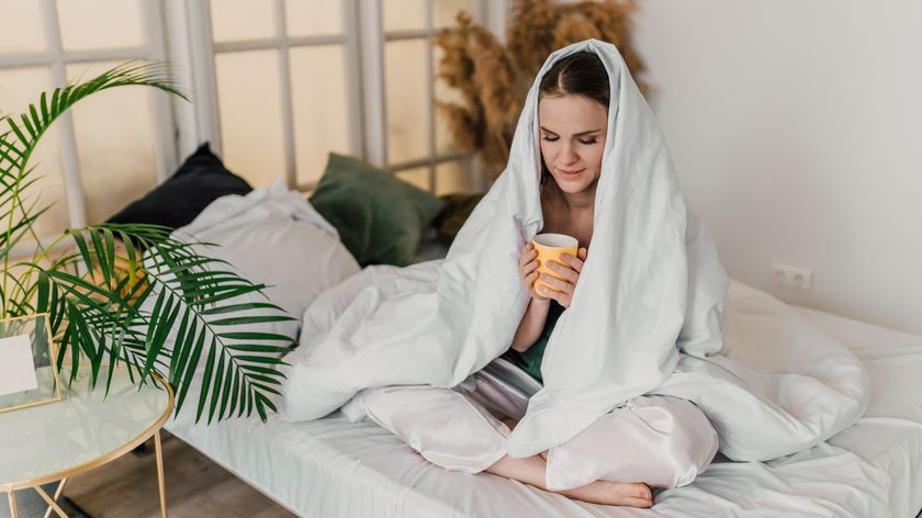 A woman sits up in bed drinking a bedtime time to help her sleep better