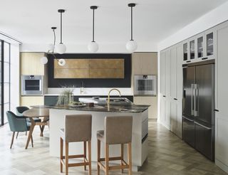 modern kitchen with unusual shaped island, herringbone floor, cabinetry, pendant lights, small table, bar stools