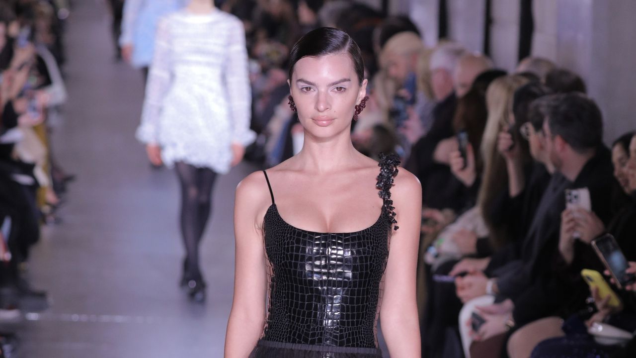 Emily Ratajkowski walking for Tory Burch in a croc-effect leotard and sheer knee-length skirt 