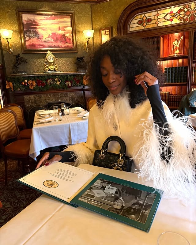 A woman sitting at a restaurant table with dark brown, curly hair