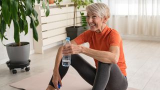 a senior woman sitting on an exercise mat