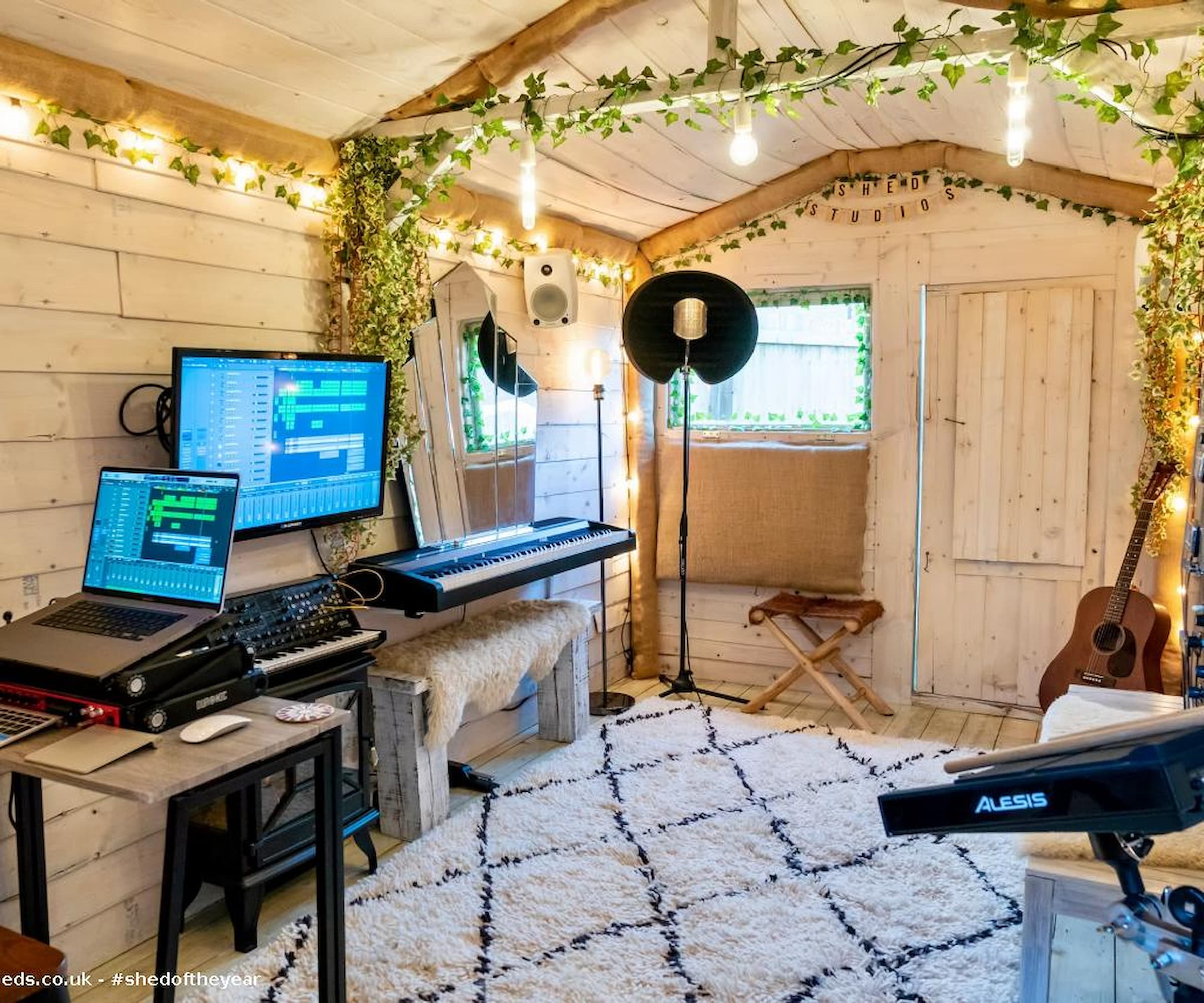 Inside a white shed with fairy lights and musical equipment and a an editing station with laptop