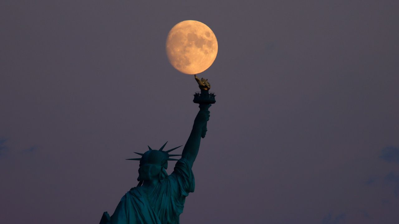 A 95 percent waxing crescent moon rises behind the Statue of Liberty in New York City on September 18, 2021 as seen from Jersey City, New Jersey.