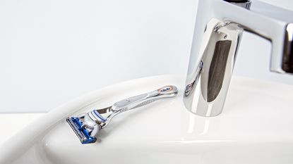 One of the best razors, a Gillette, sitting on a bathroom sink next to a tap
