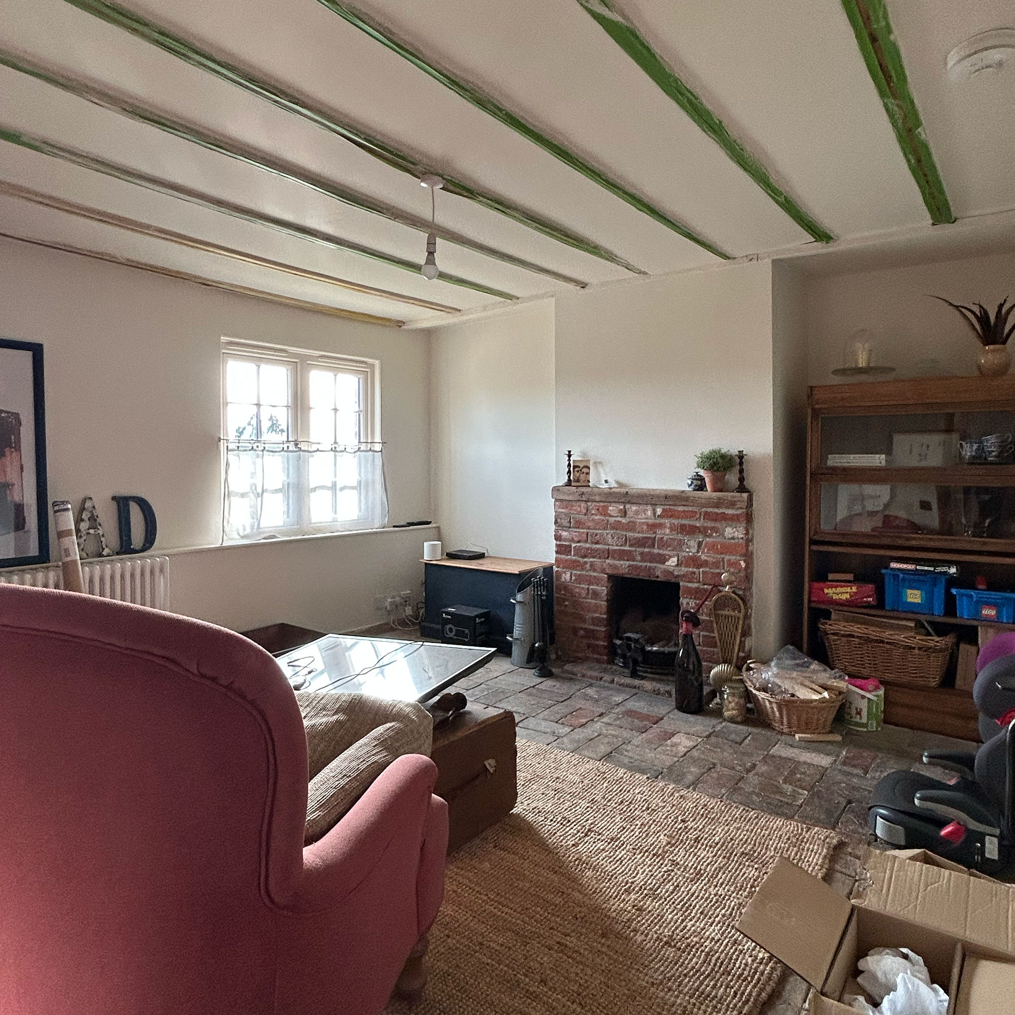 Unfinished living room with beams primed for painting, cardboard boxes and shadeless light