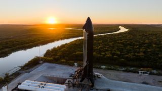 A SpaceX Starship spacecraft on a test stand with the setting sun for Flight 7