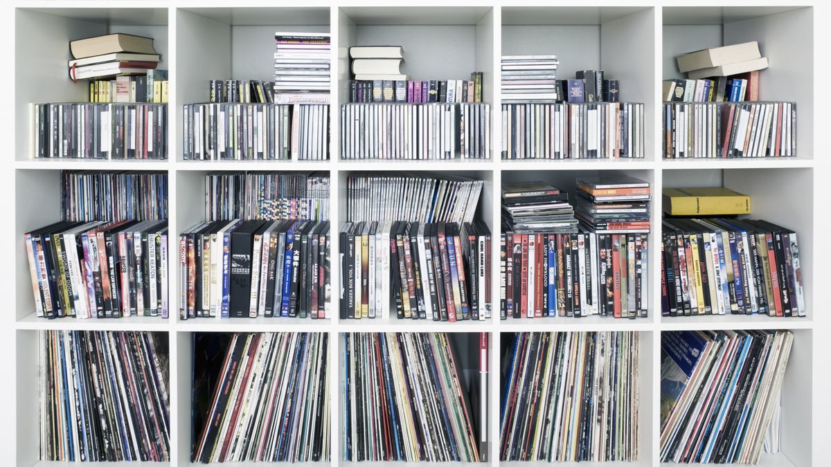 A white bookshelf filled with CDs and records