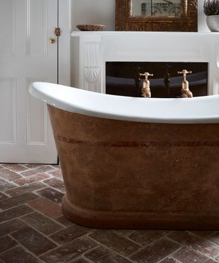 Rustic bathroom with white fireplace, tub and terracotta tiles