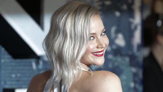 Jennifer Lawrence smiling at the camera with silver hair and red lipstick