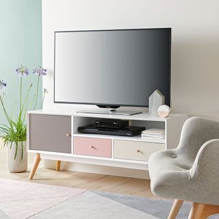 white and blue wall with white tv table and tv