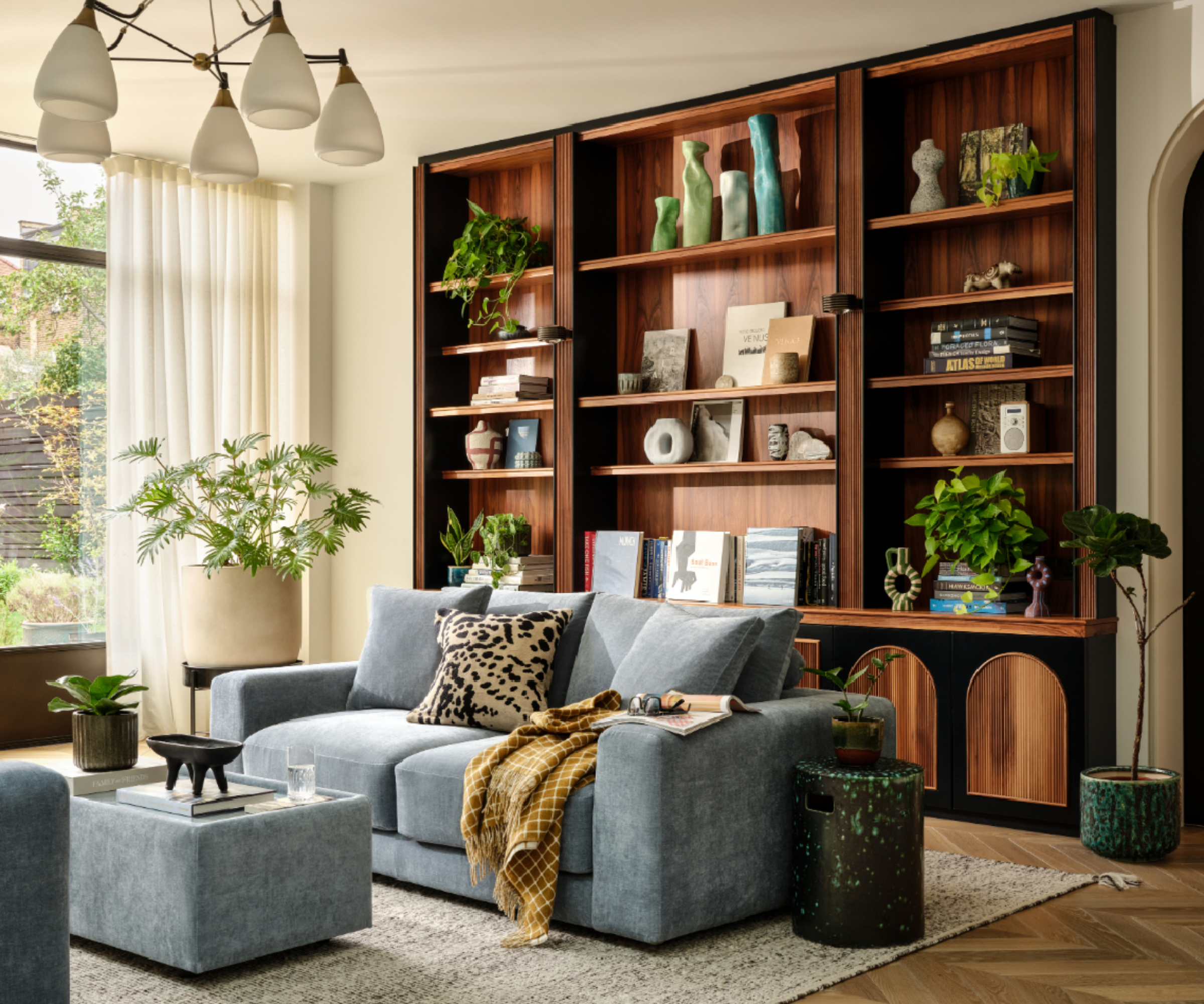 living room with built in dark wooden shelving with curated books and decor, blue sofas
