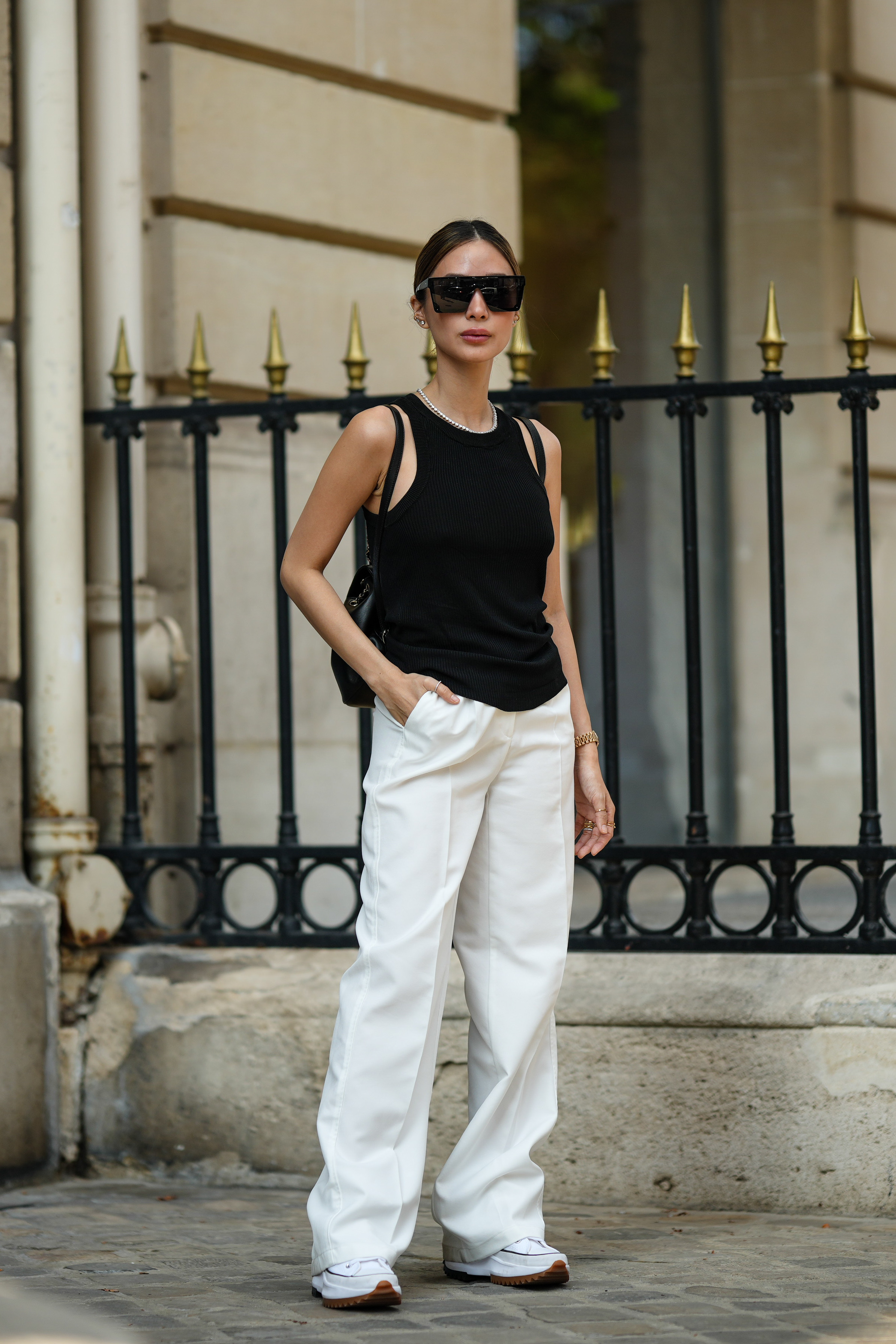 woman wearing black tank top, white pants, and sneakers